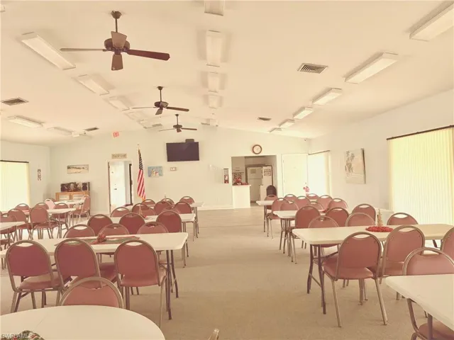 Carpeted open space or dining area featuring vaulted ceiling and ceiling fan