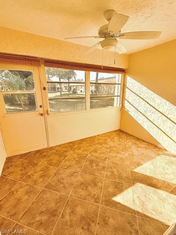 Unfurnished sunroom featuring a wealth of natural light and ceiling fan