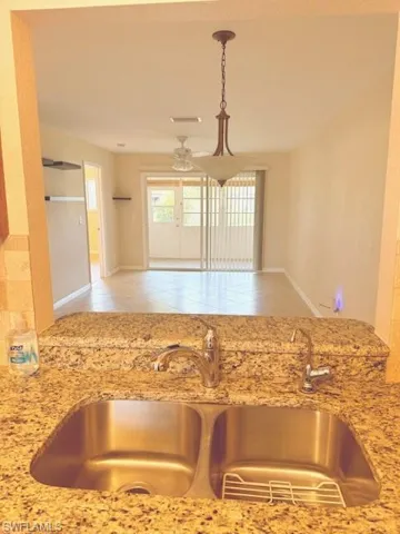 Kitchen looking at dining/living room with hanging light fixtures, ceiling fan, and light tile patterned floors