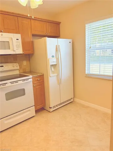 Kitchen featuring light tile patterned floors, white appliances, and tasteful backsplash