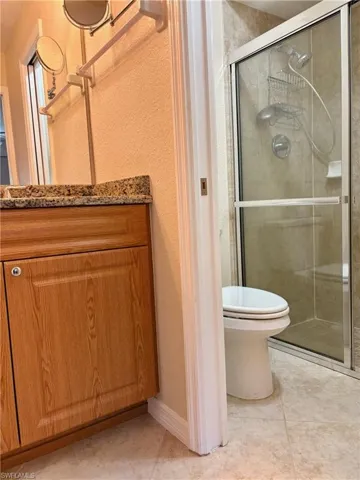 Bathroom with tile patterned flooring, toilet, an enclosed shower, and vanity