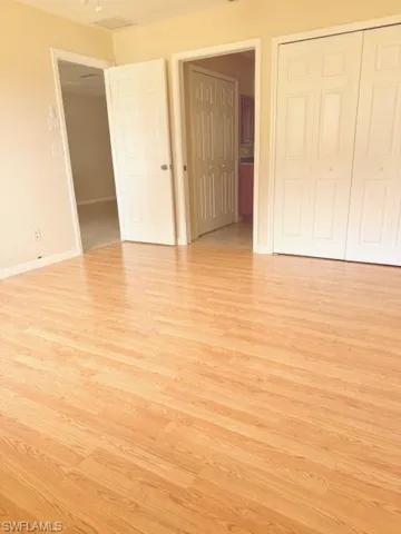 Unfurnished bedroom with light hardwood / wood-style floors, ensuite bath, and a closet