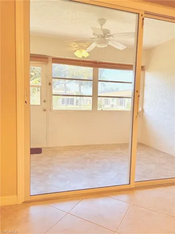 Doorway to outside featuring tile patterned flooring, plenty of natural light, ceiling fan, and a textured ceiling