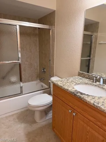 Full bathroom featuring tile patterned flooring, vanity, combined bath / shower with glass door, and toilet