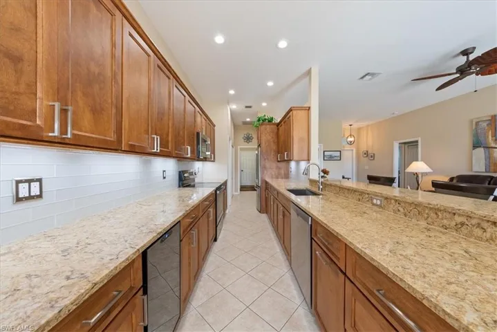 Kitchen featuring stainless steel appliances, light stone countertops, sink, and backsplash