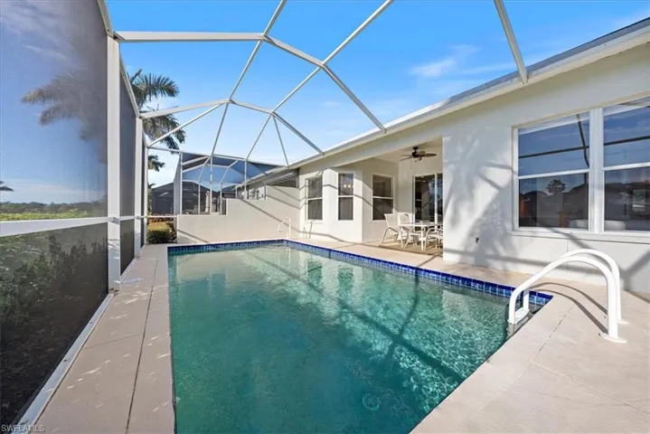 View of swimming pool featuring ceiling fan, a patio, and glass enclosure