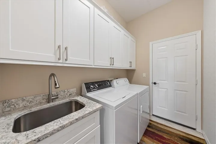 Washroom with cabinets, sink, and washer and dryer