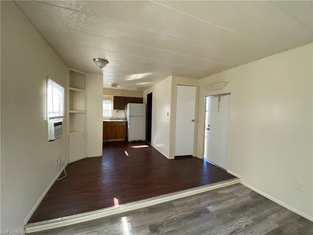 Unfurnished living room with built in features, dark wood-style floors, a textured ceiling, and cooling unit