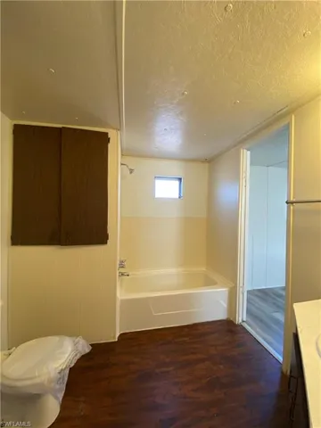 Full bathroom featuring a bath, dark wood-type flooring, a textured ceiling, and vanity