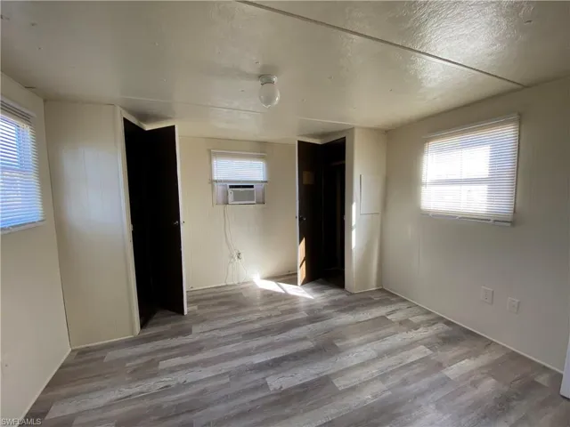 Unfurnished bedroom featuring light wood finished floors, a closet, a textured ceiling, and cooling unit
