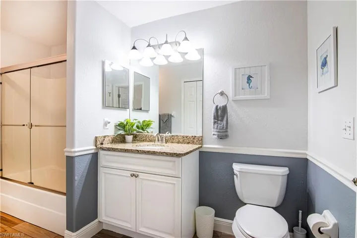 Full bathroom featuring combined bath / shower with glass door, vanity, and toilet