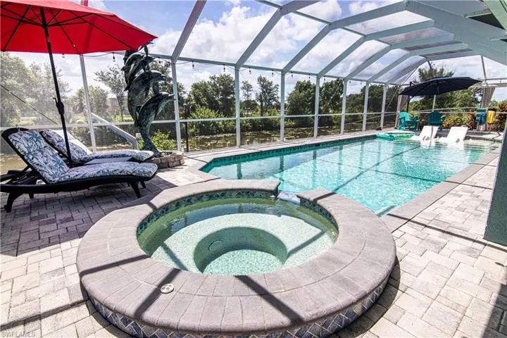 View of swimming pool featuring a patio area, a lanai, and an in ground hot tub