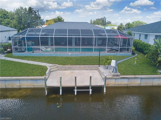 Back of property featuring a patio area, a lawn, a lanai, and a water view
