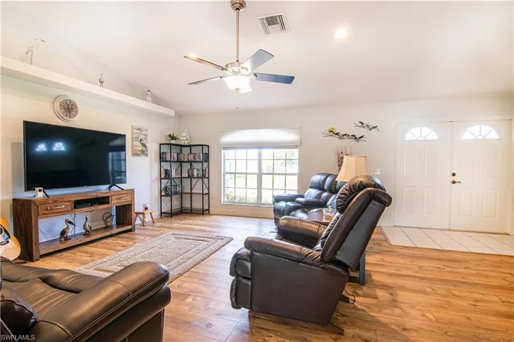 Living room featuring high vaulted ceiling, wood-type flooring, and ceiling fan
