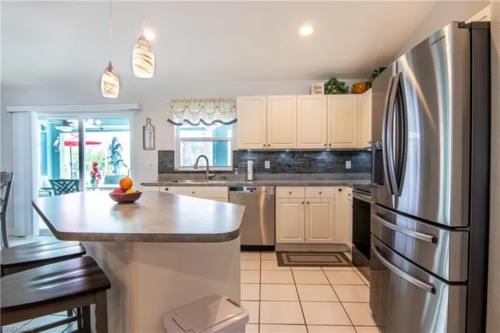 Kitchen featuring decorative light fixtures, light tile flooring, stainless steel appliances, tasteful backsplash, and sink