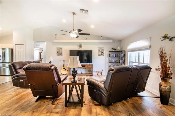 Living room featuring vaulted ceiling, ceiling fan, and hardwood / wood-style flooring