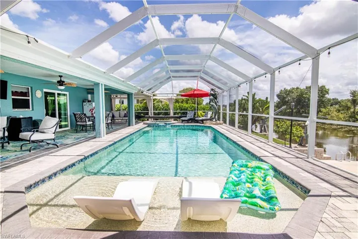 View of pool with a patio, glass enclosure, and ceiling fan