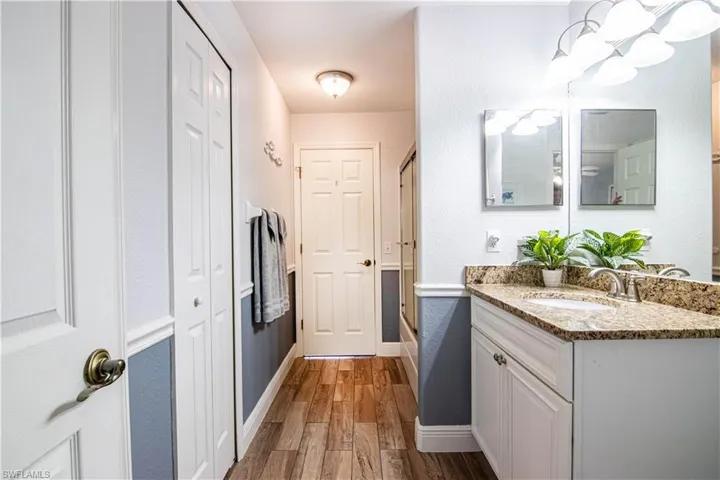 Bathroom with shower / bath combination with glass door, wood-type flooring, and vanity