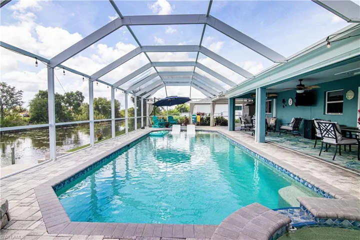 View of swimming pool featuring ceiling fan, outdoor lounge area, glass enclosure, and a patio