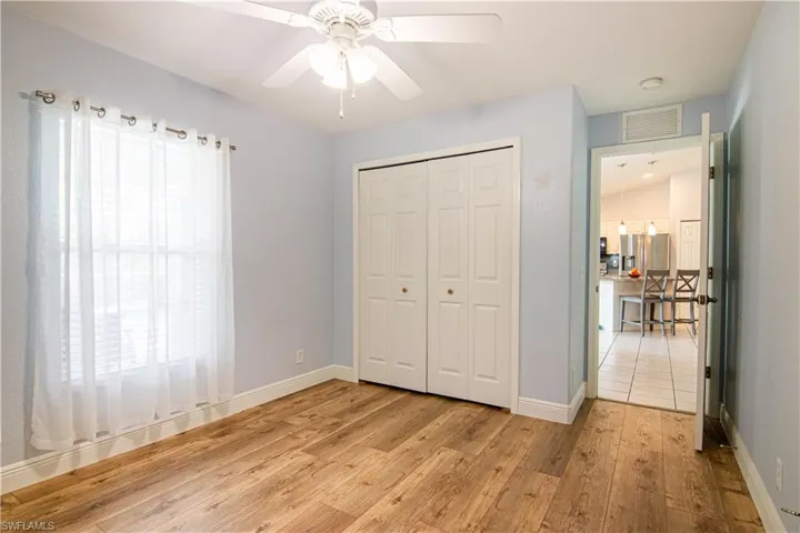 Unfurnished bedroom featuring a closet, ceiling fan, light hardwood / wood-style floors, and lofted ceiling