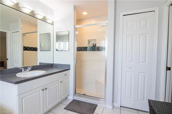 Bathroom featuring a shower with door, tile flooring, and vanity