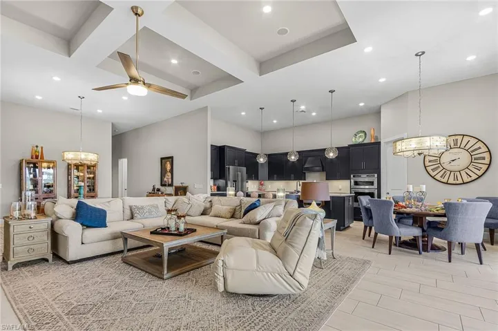 Living room with a chandelier, ceiling fan, coffered ceiling, and wood tiled floors