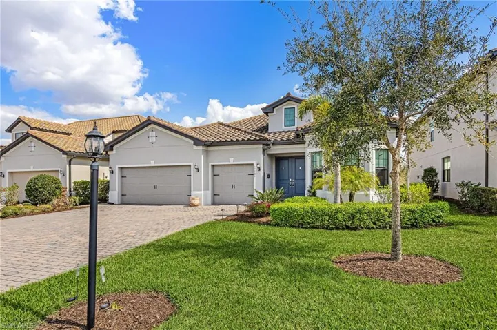 Mediterranean / spanish home with decorative driveway, stucco siding, a garage, a tiled roof, and a front lawn
