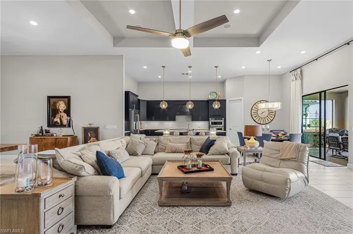 Living room featuring a ceiling fan, a high tray ceiling, and a chandelier