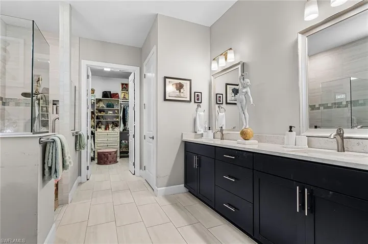Full bath featuring a stall shower, double vanity, and a walk in closet