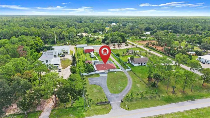 Property with expansive green spaces and mature trees, featuring a paved circular drive and gated entry