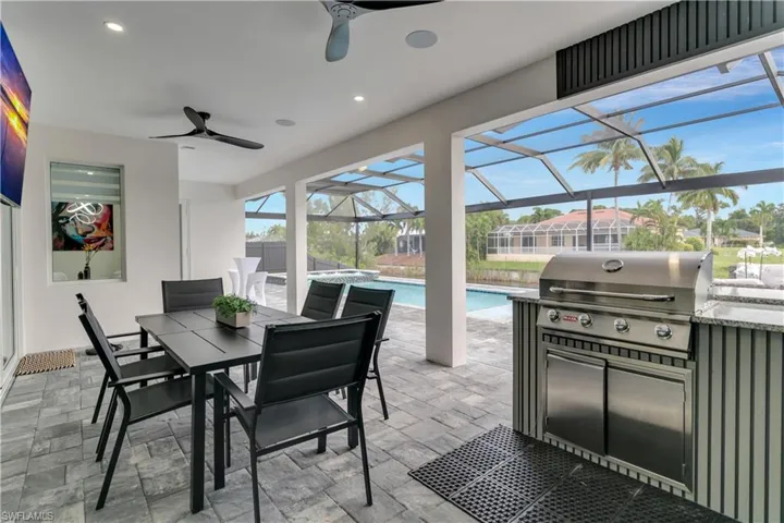 View of patio featuring exterior kitchen, an outdoor pool, outdoor dining area, a ceiling fan, and a grill