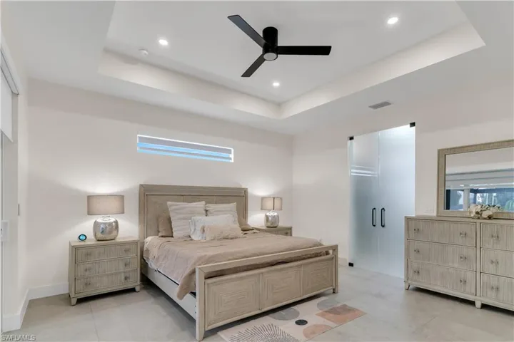 Bedroom with recessed lighting, visible vents, multiple windows, and a raised ceiling