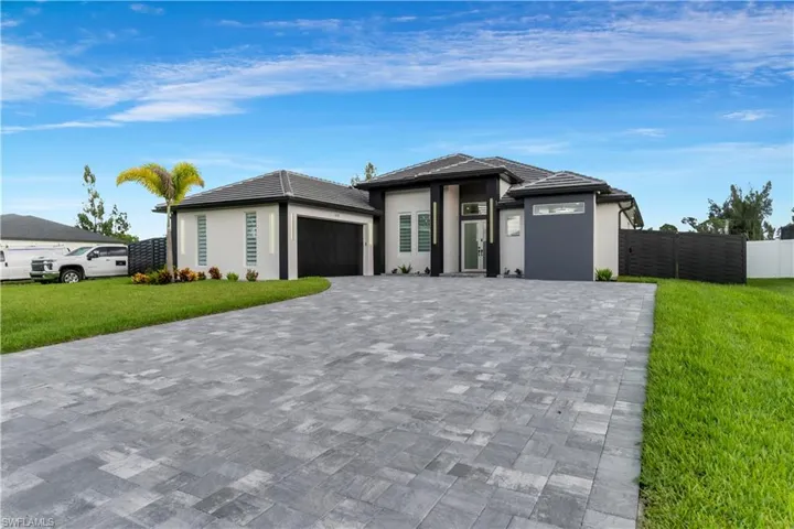Prairie-style house with a garage, fence, decorative driveway, and a front yard