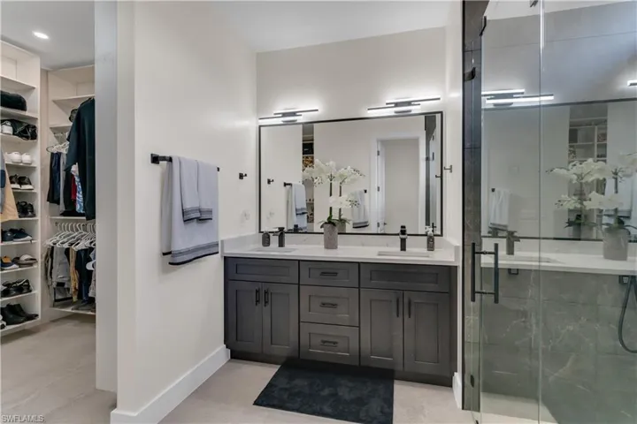Bathroom featuring double vanity, a sink, and a stall shower