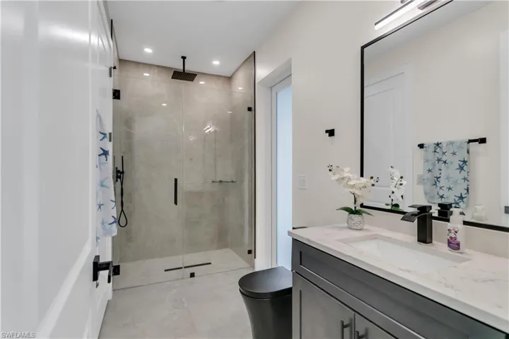 Bathroom featuring a shower stall, vanity, tile patterned floors, toilet, and recessed lighting