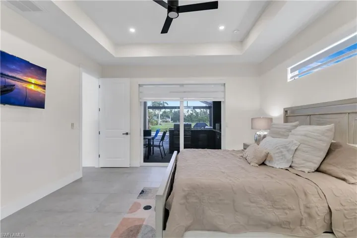 Bedroom with ceiling fan, visible vents, access to exterior, baseboards, and a tray ceiling