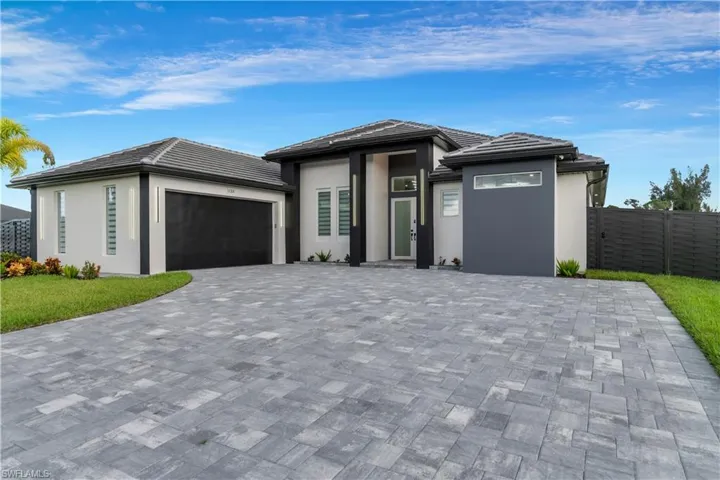 Prairie-style home with a tiled roof, an attached garage, fence, and stucco siding