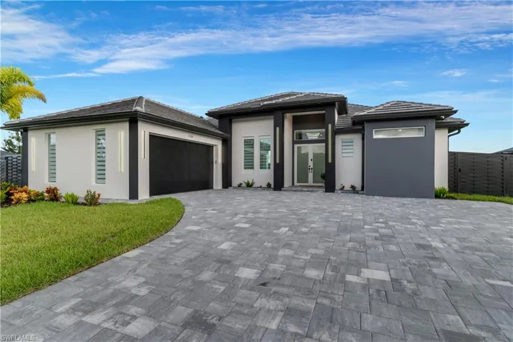 Prairie-style home with a tiled roof, a front yard, a garage, decorative driveway, and stucco siding