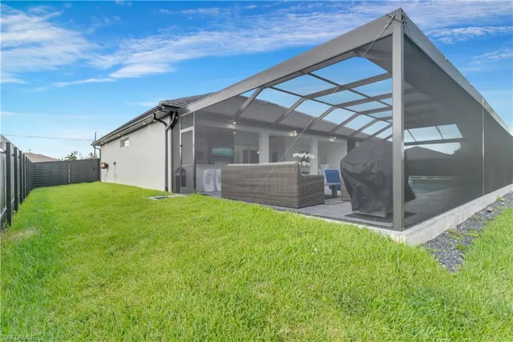 Rear view of property featuring stucco siding, a fenced backyard, a patio area, a lanai, and a yard
