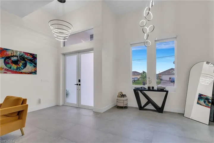Entryway with an inviting chandelier, baseboards, french doors, and concrete flooring