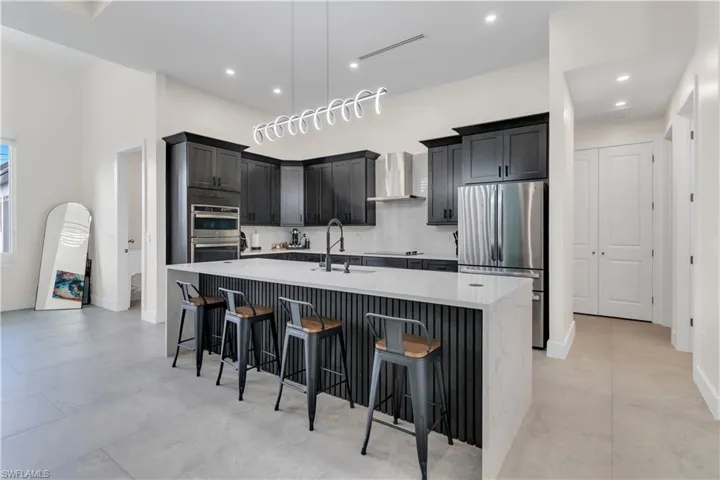 Kitchen featuring a kitchen breakfast bar, appliances with stainless steel finishes, a spacious island, a sink, and recessed lighting