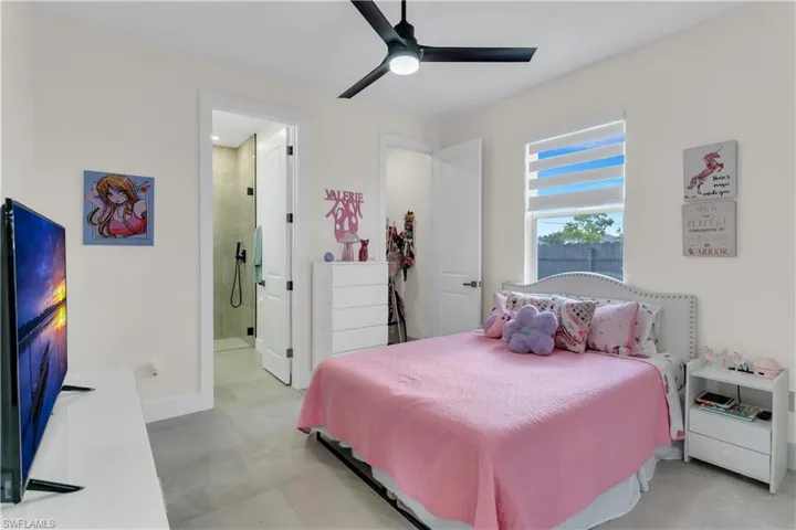 Bedroom featuring baseboards, ensuite bathroom, and a ceiling fan