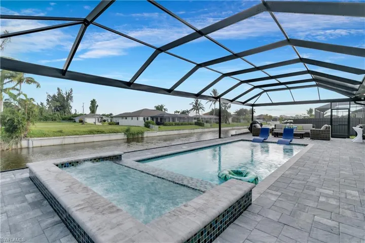 View of pool with glass enclosure, a patio, a pool with connected hot tub, and outdoor lounge area