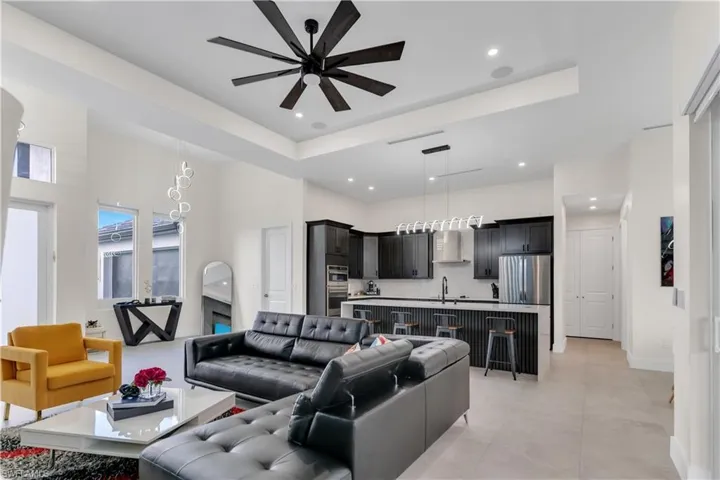 Living area featuring a high ceiling, a ceiling fan, baseboards, recessed lighting, and a tray ceiling