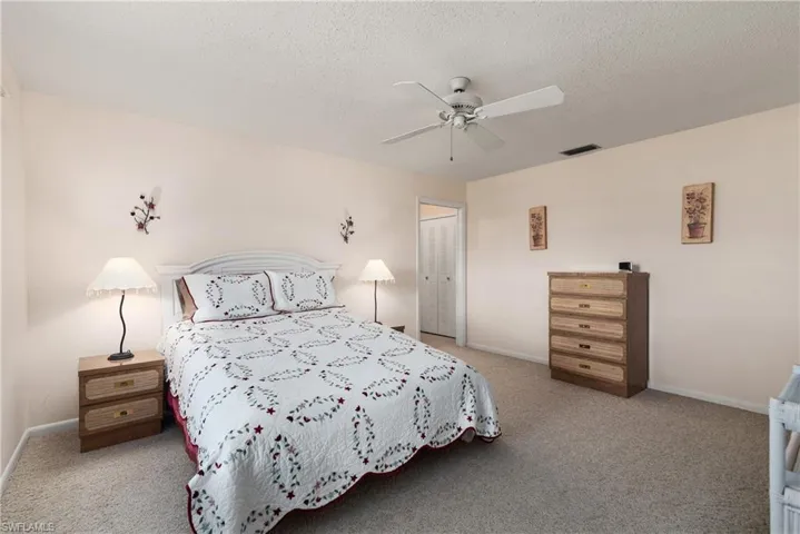 Bedroom with light colored carpet, ceiling fan, and a textured ceiling