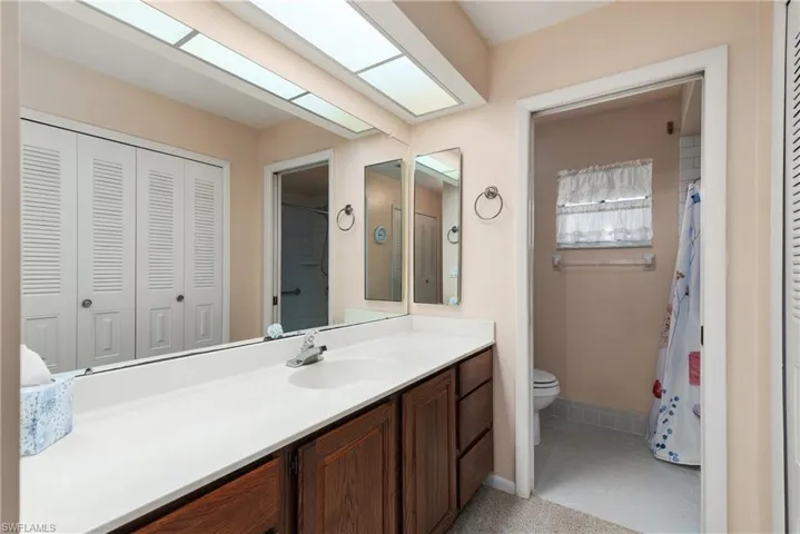 Full bath featuring a closet, vanity, a shower with shower curtain, and light tile patterned floors