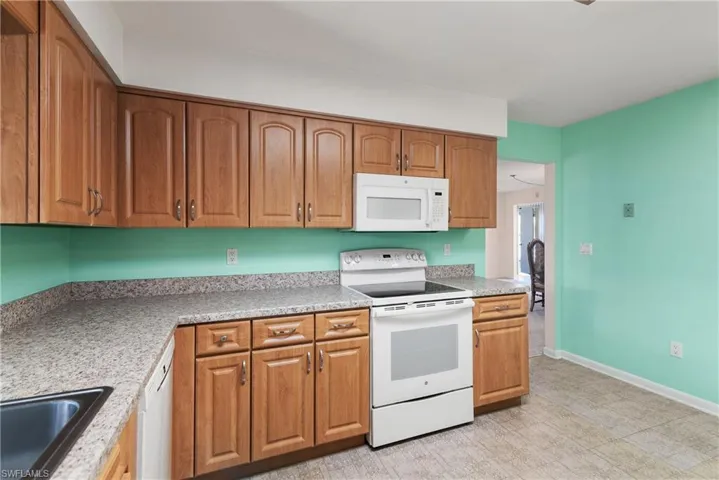 Kitchen featuring white appliances, brown cabinetry, and light floors