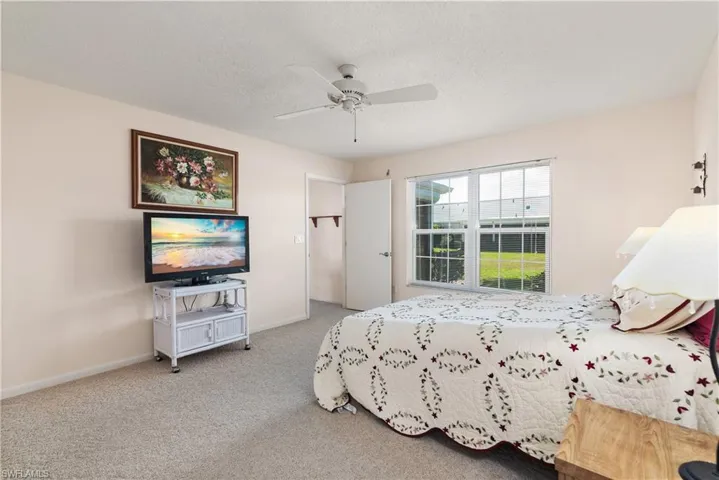 Carpeted bedroom with ceiling fan and a textured ceiling