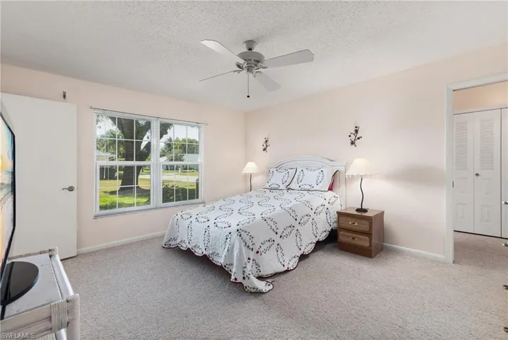 Bedroom featuring light colored carpet, ceiling fan, and a textured ceiling