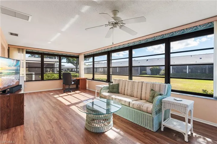 Sunroom featuring a textured ceiling, wood finished floors, and built in desk